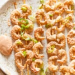 shrimp skewers with dipping sauce on a plate.