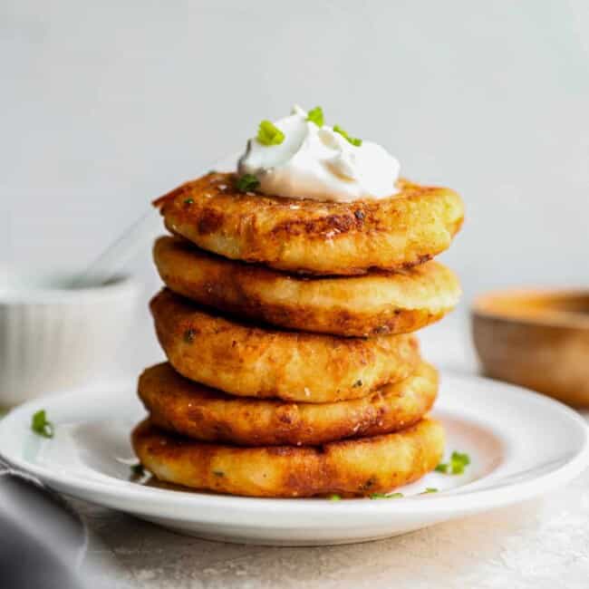 a stack of potato pancakes with sour cream and chives.