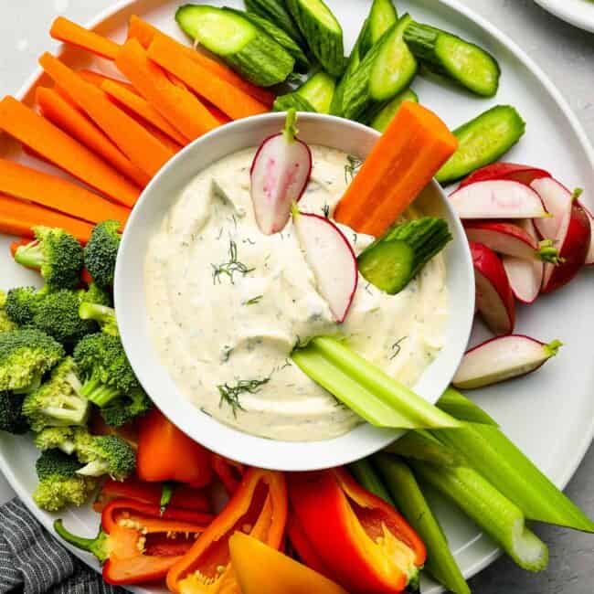 a bowl of dip surrounded by vegetables.