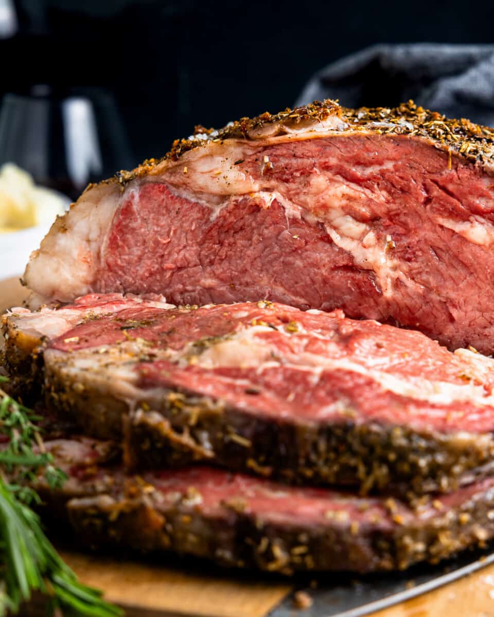 close up of a partially sliced prime rib roast on a cutting board.