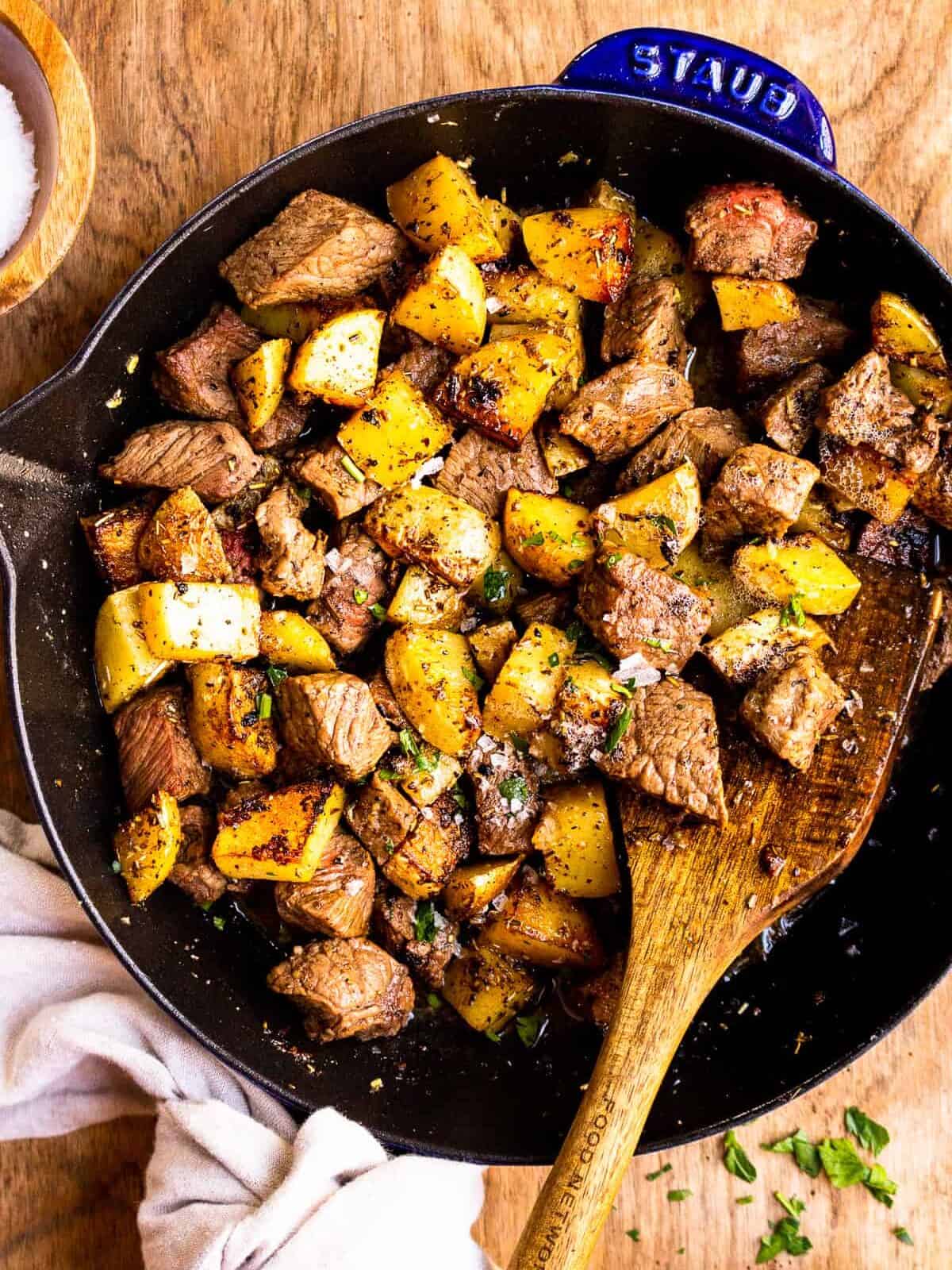 garlic butter steak bites with potatoes in skillet