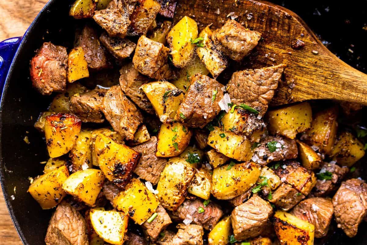 up close garlic butter steak bites with potatoes in skillet