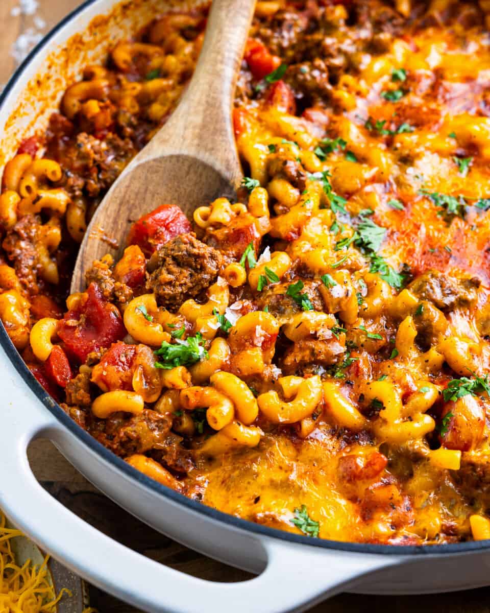 american chop suey in a skillet with a wooden spoon.