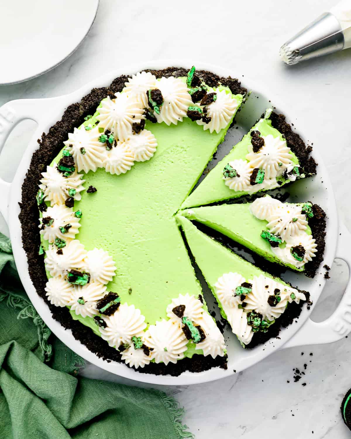 a partially sliced green mint chocolate pie in a white pie pan.