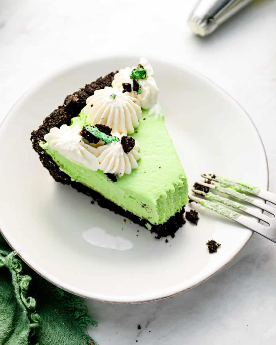 a slice of grasshopper pie on a white plate with a fork.
