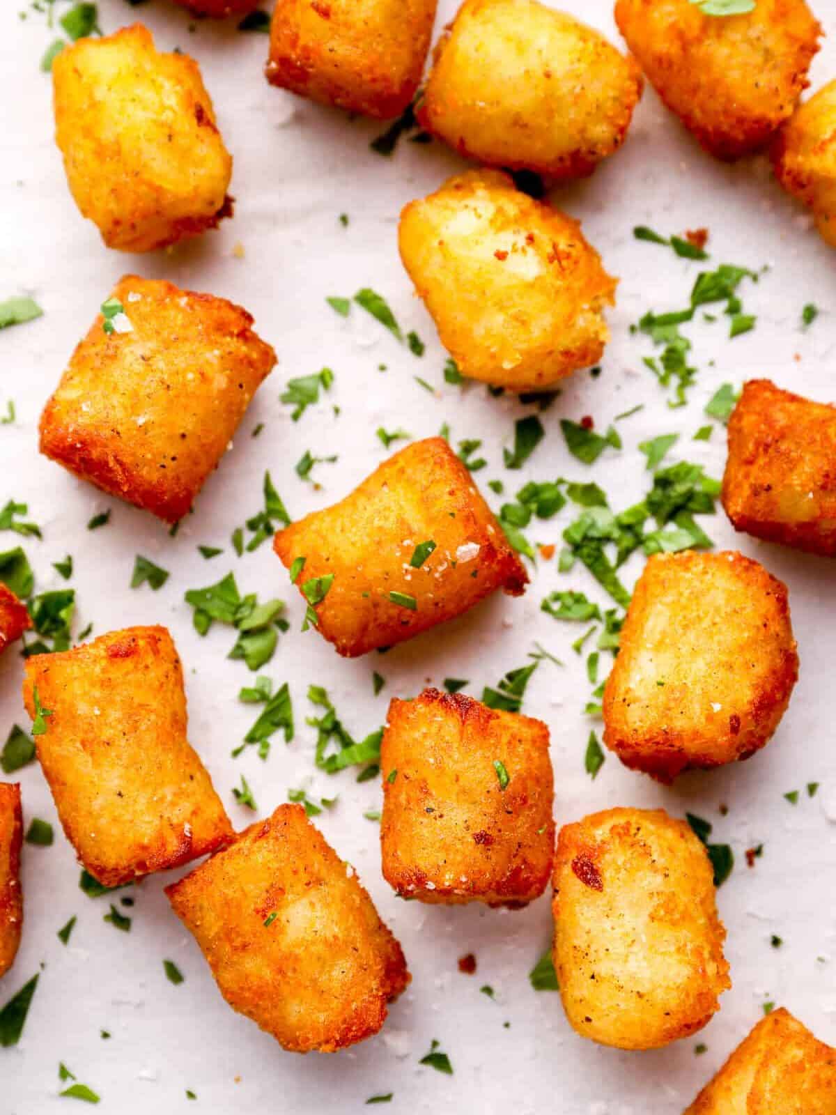 overhead view of scattered baked tater tots topped with parsley.