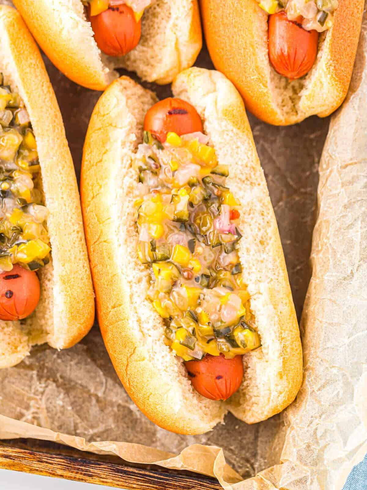 close up overhead view of a hot dog topped with pickle relish in a baking pan.