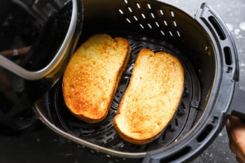 grilled cheese sandwiches in an air fryer basket.