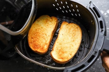 grilled cheese sandwiches in an air fryer basket.