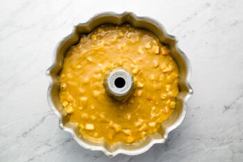 a cake batter in a metal pan on a marble countertop.