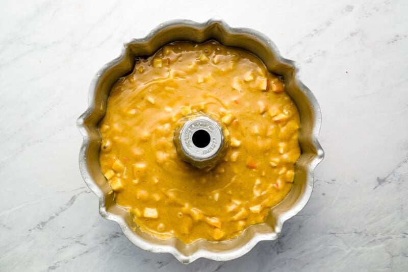 a cake batter in a metal pan on a marble countertop.