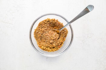 granola in a glass bowl with a spoon.