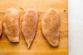 four chicken breasts on a cutting board.