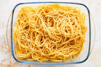 spaghetti in a glass bowl on a white surface.