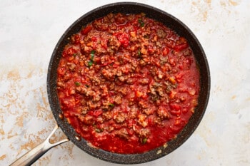 a skillet filled with meat and tomato sauce.