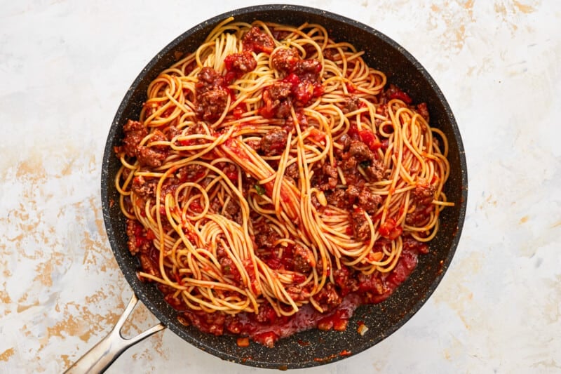 a skillet filled with spaghetti and meat sauce.