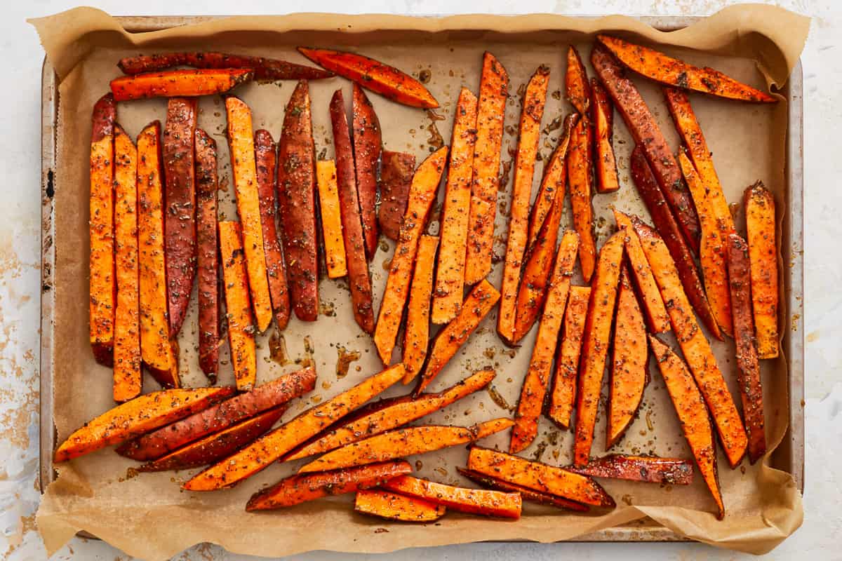 Raw seasoned sweet potato fries on a baking sheet.