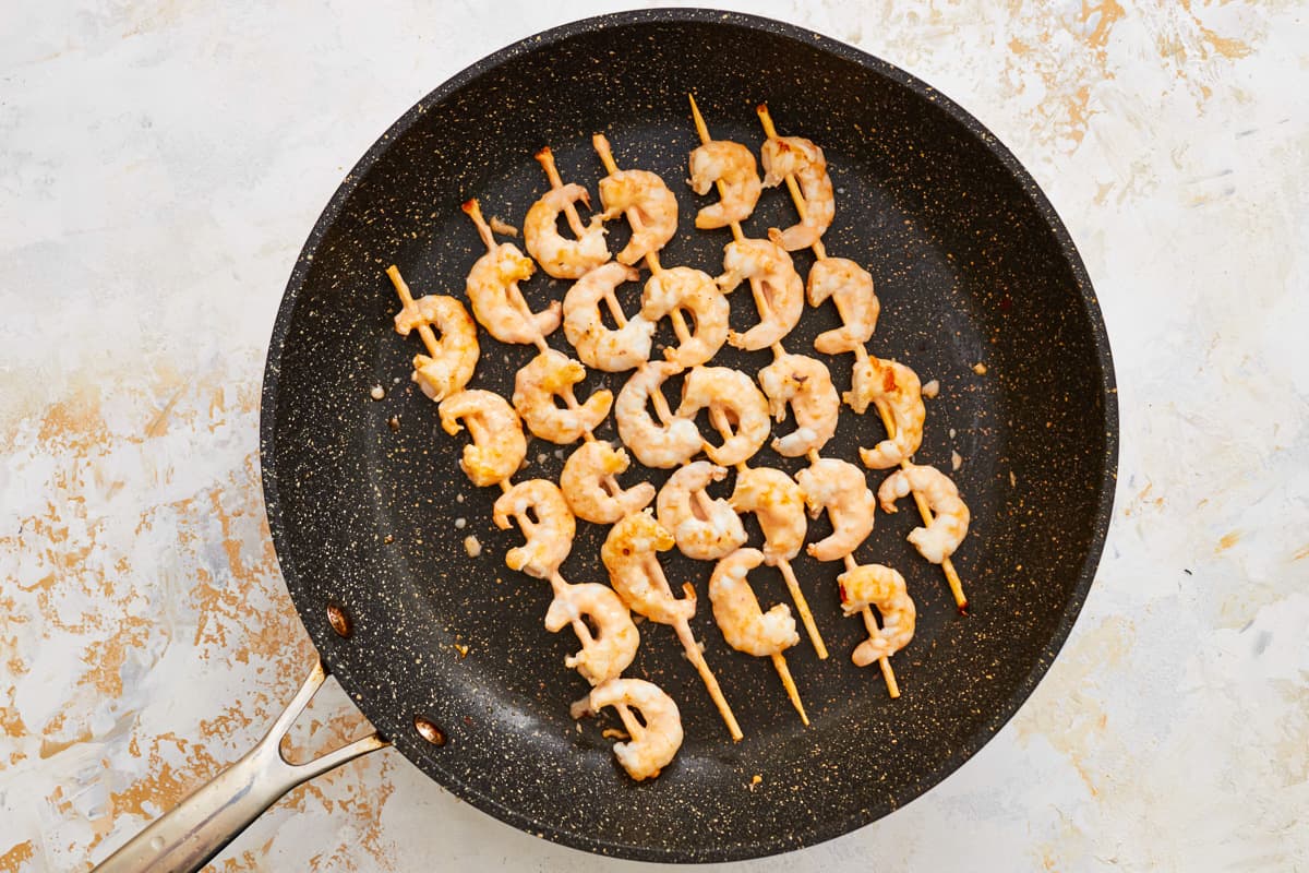 shrimp on skewers in a frying pan.