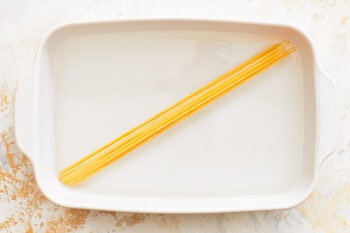 a white dish with a yellow stick of spaghetti on it.