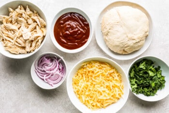the ingredients for a cheesy chicken pizza.