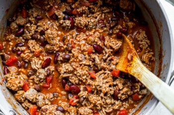 chili in a pot with a wooden spoon.