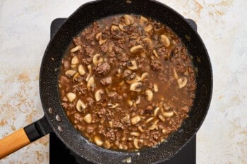 a frying pan filled with beef and mushrooms.