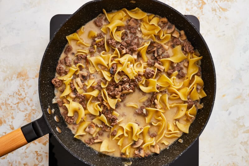 a skillet with noodles and meat in it.