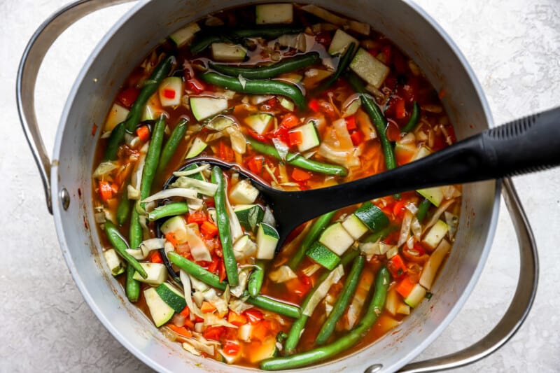 overhead view of cabbage soup in a dutch oven with a serving spoon.