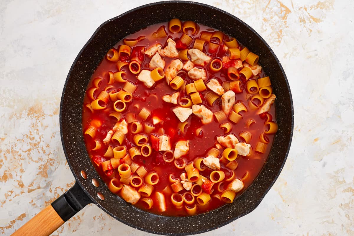 a frying pan filled with pasta and tomato sauce.