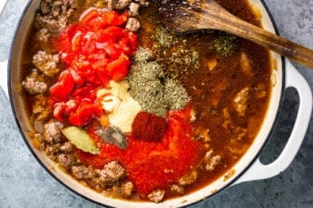 a pot with meat, vegetables and spices in it.