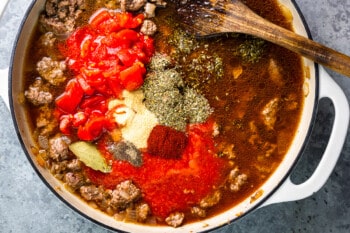 a pot with meat, vegetables and spices in it.