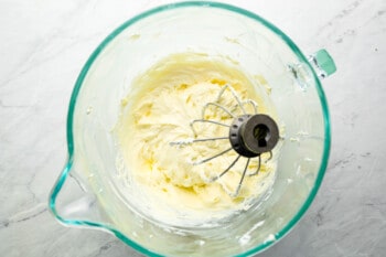 whipped cream in a glass bowl with a whisk.