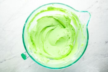 a bowl of green icing in a glass bowl.
