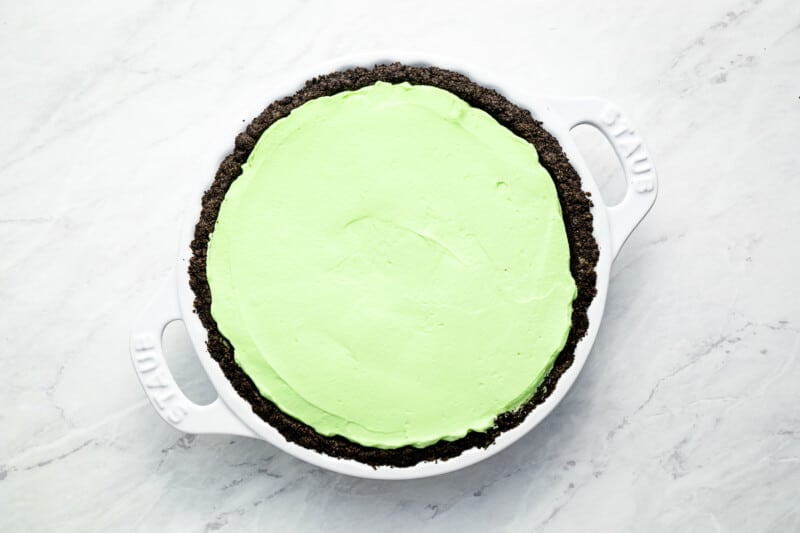 a pie with a green icing in a white dish.