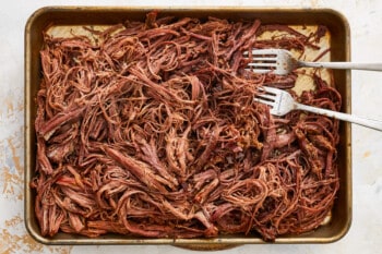 shredded beef in a baking pan with a fork.