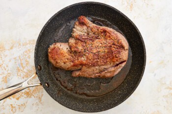 a steak in a frying pan on a white background.