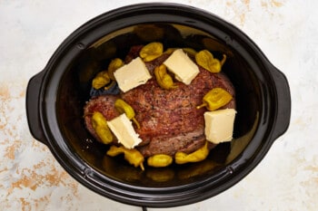 a crock pot filled with meat and vegetables.