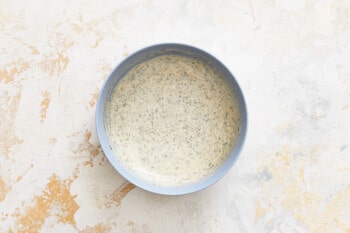 a blue bowl of dressing on a white surface.