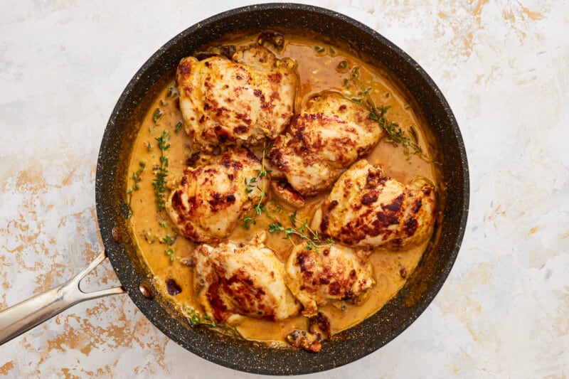 chicken breasts in a sauce in a skillet.