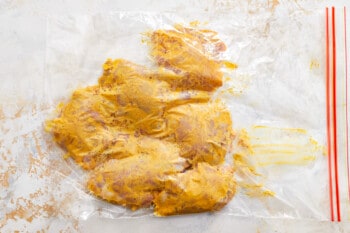 chicken breasts in a plastic bag on a white surface.