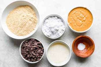 ingredients for peanut butter cookie dough in bowls on a white background.