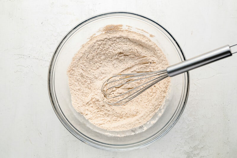a bowl of flour with a whisk in it.