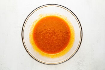 a bowl of orange sauce on a white background.