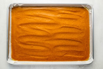 a baking pan with a layer of carrot cake in it.