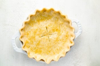 a pie in a white dish on a white surface.