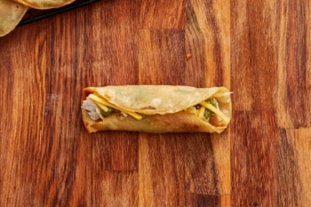 chinese spring rolls on a wooden cutting board.