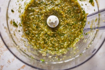 a food processor filled with green sauce.