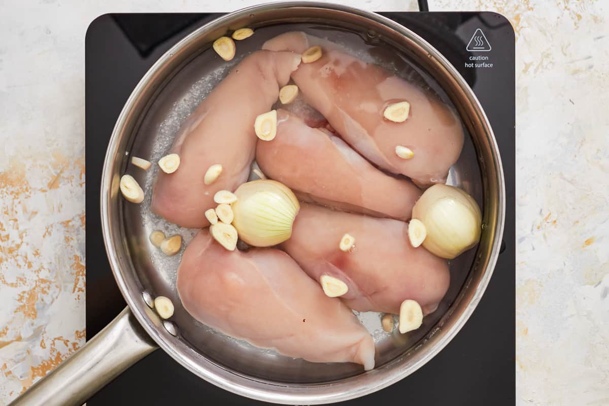 chicken in a pan with onions and garlic.