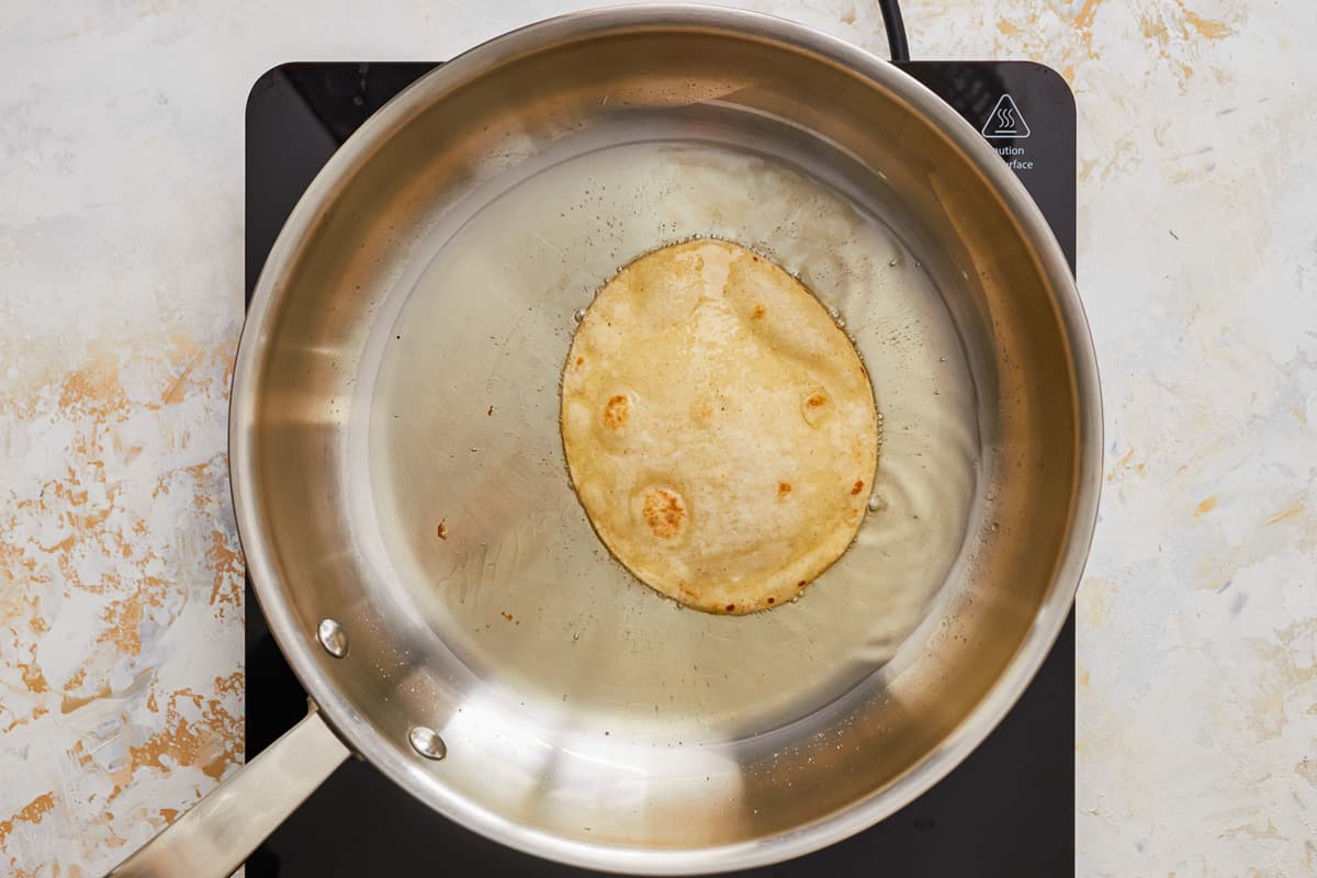 a tortilla is being cooked in a pan on a stove.
