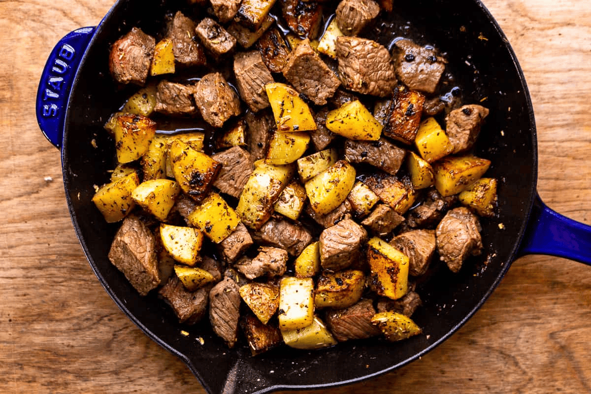Steak and potatoes in a cast iron skillet. 